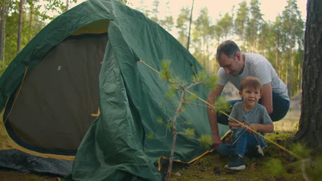 Father-and-son-together-set-up-a-tent-in-the-woods-during-the-summer-campaign.-Father-and-son-put-up-a-tent-in-the-autumn